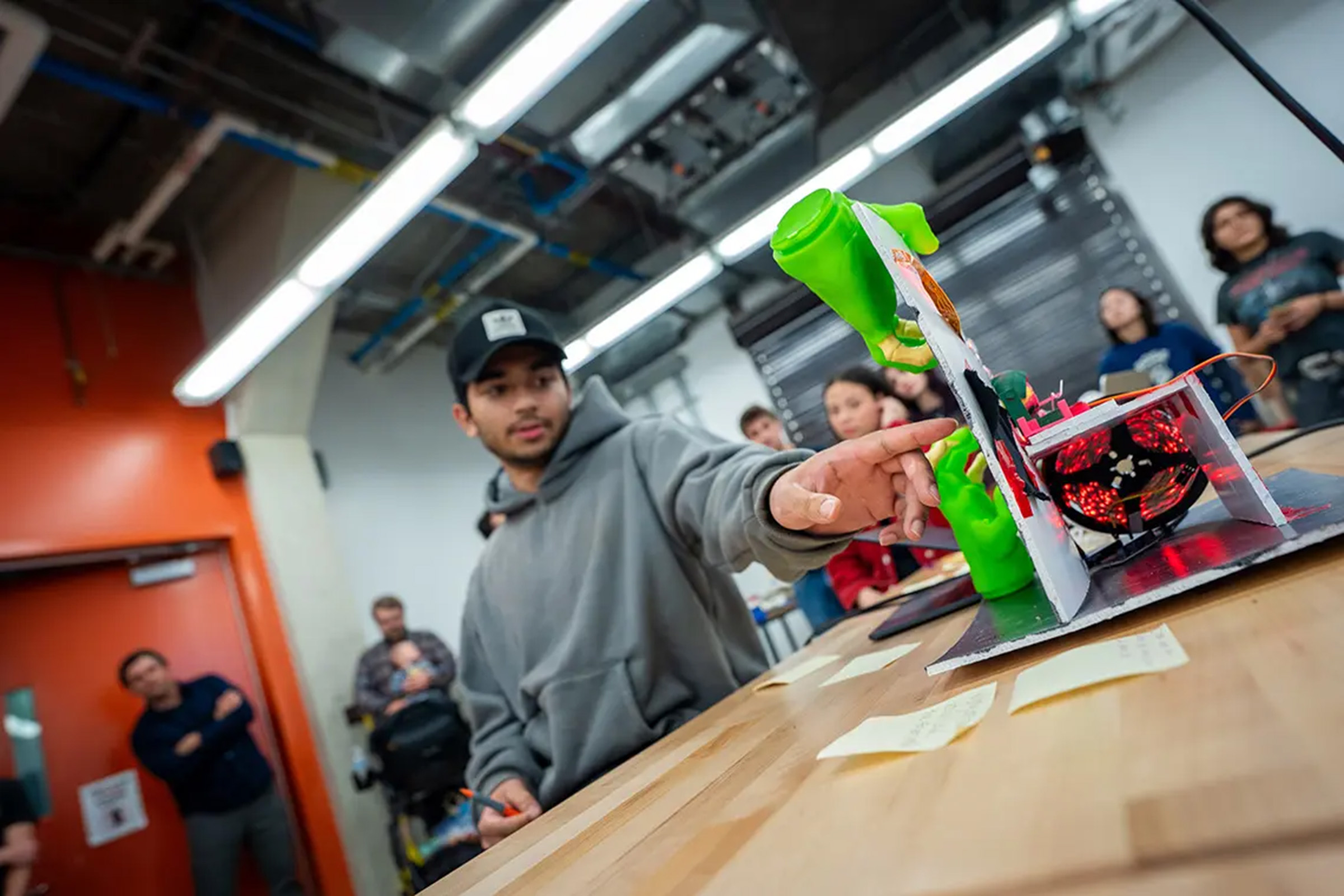 Student gestures toward robotic device on desk